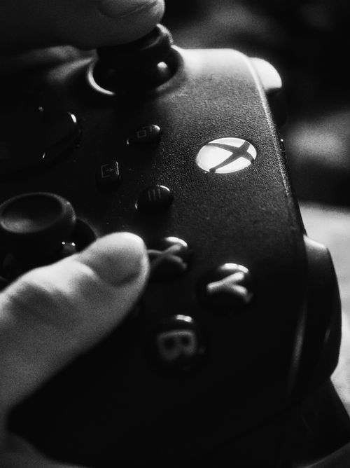 Free Black and white close-up of a hand holding a gaming controller, focusing on buttons. Stock Photo