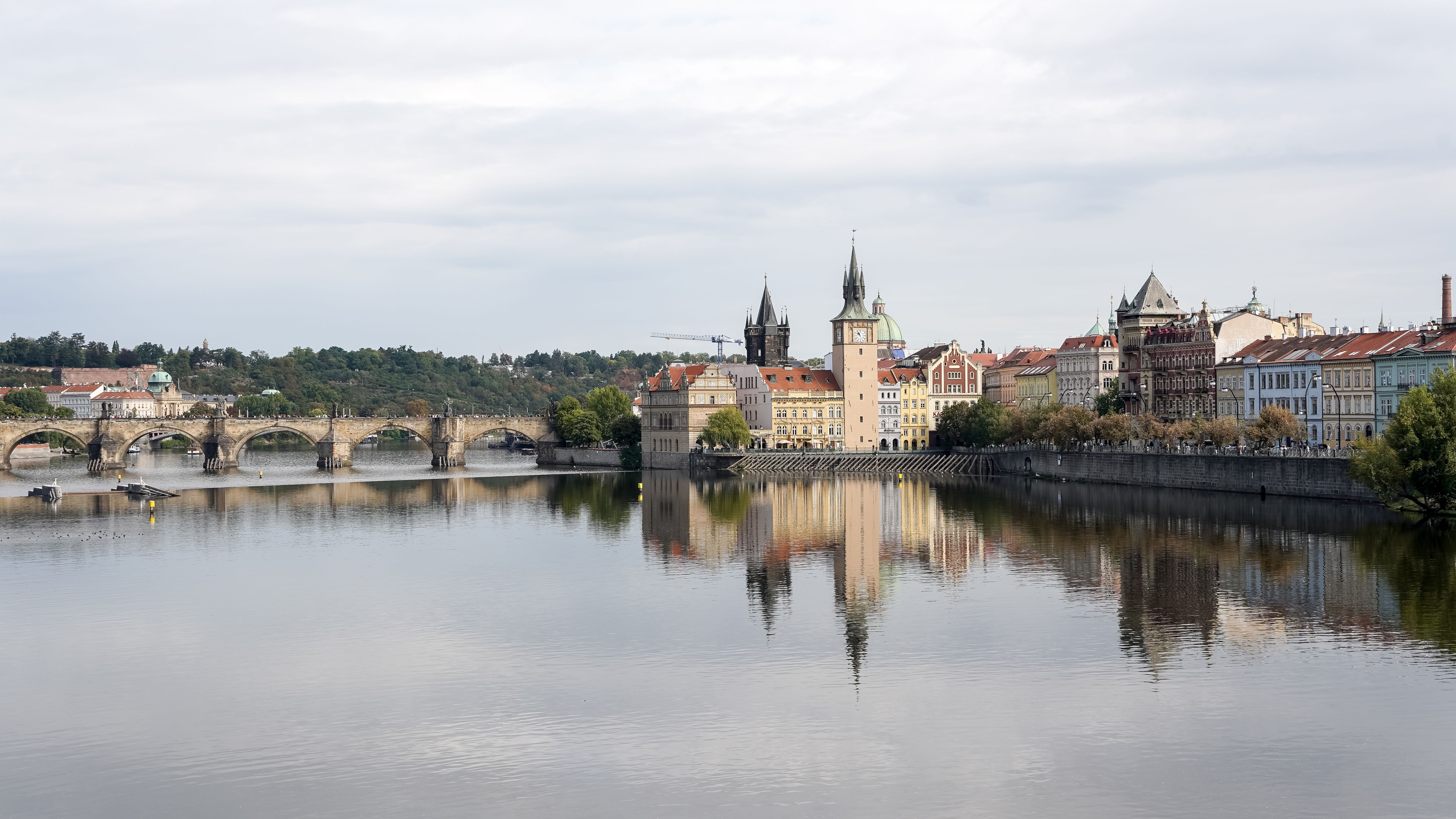 A serene panorama of Prague's historic waterfront, showcasing iconic architecture and Vltava River reflections.