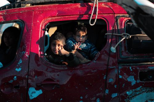 Free Children peering from an aged vehicle, capturing candid childhood expressions. Stock Photo