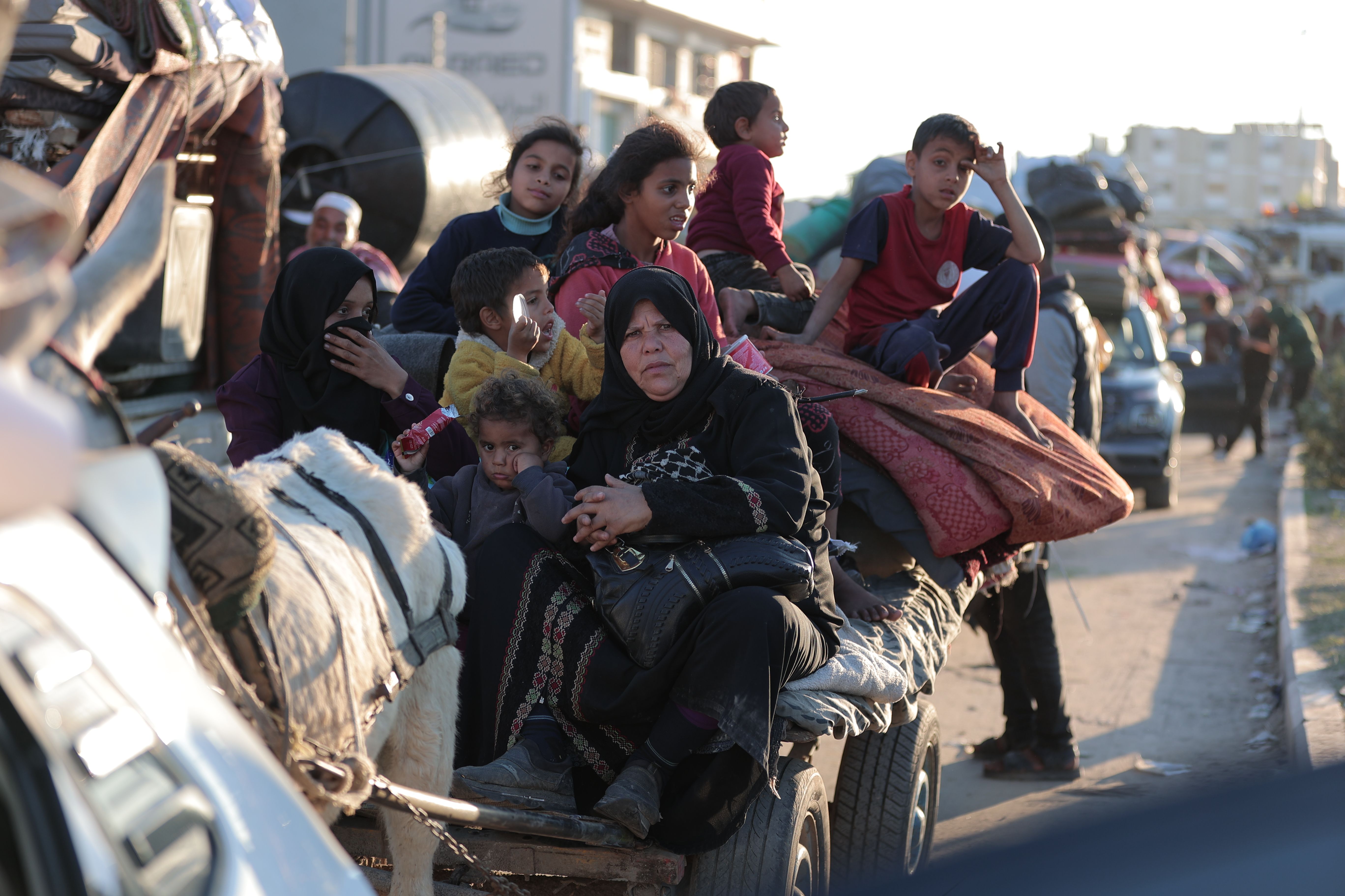 A group of people sitting together on a roadside with belongings, conveying a journey.