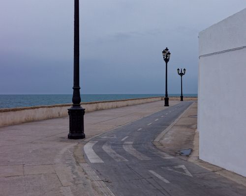 Free Empty coastal promenade with vintage street lamps against a calm sea backdrop. Stock Photo