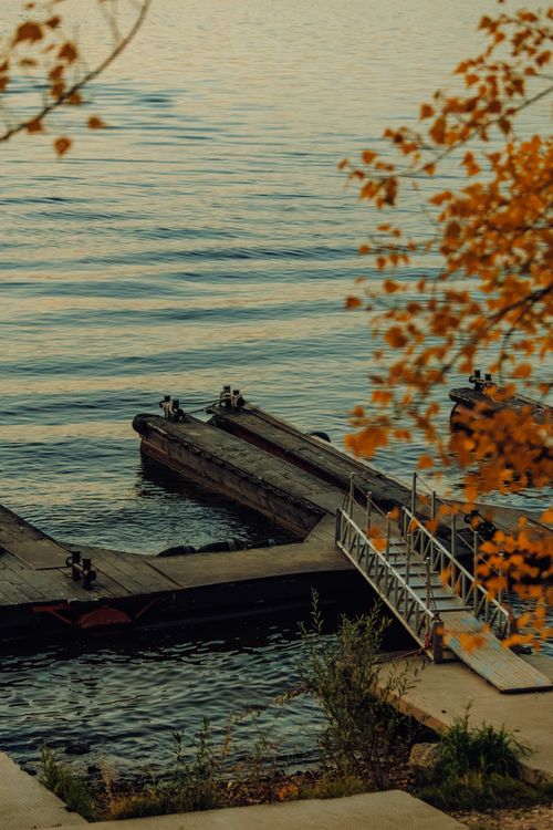 Free Peaceful dock scene with autumn leaves and tranquil water. Perfect for relaxation and nature themes. Stock Photo