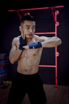 Young man with athletic build practicing boxing moves in a gym setting.