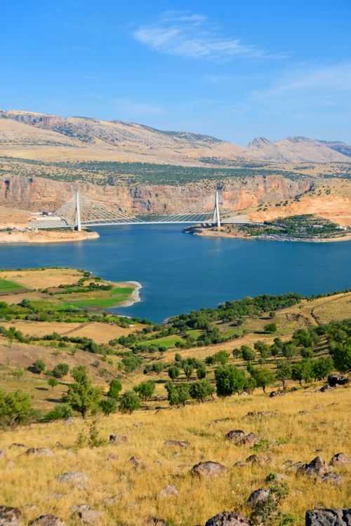 Free Beautiful landscape featuring a suspension bridge over a serene river. Stock Photo