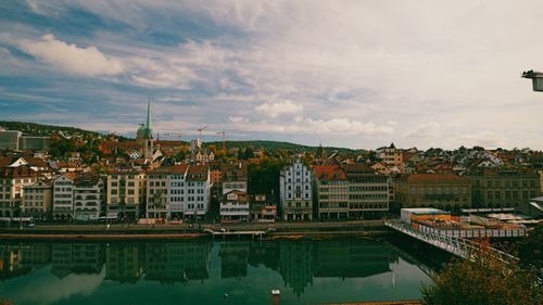 Free Scenic view of Zurich's historical buildings reflecting over the serene Limmat River under a vibrant sky. Stock Photo