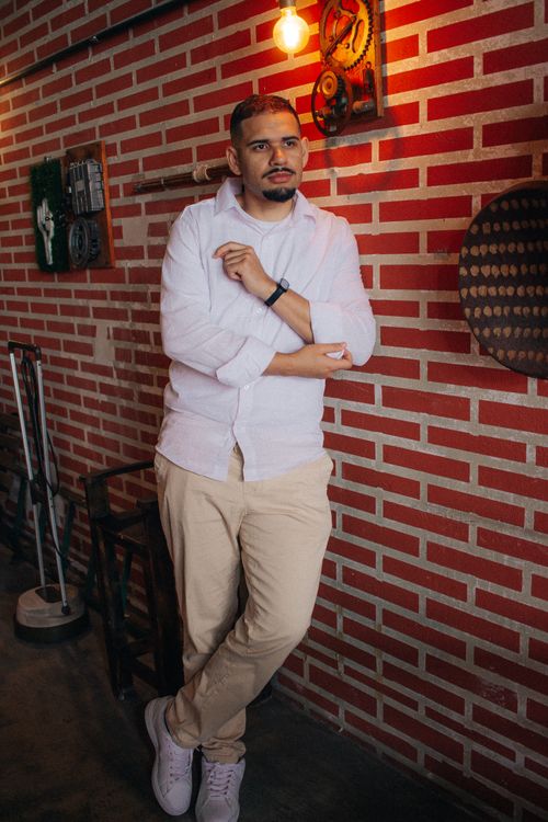 Free A man in casual attire leaning against a brick wall in a cafe with industrial decor. Stock Photo