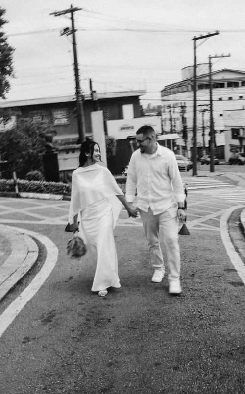 Free Couple holding hands in urban setting, dressed in white. Romantic street scene. Stock Photo