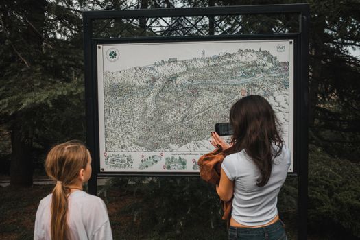 Two people explore an intricate outdoor park map nestled in lush greenery.
