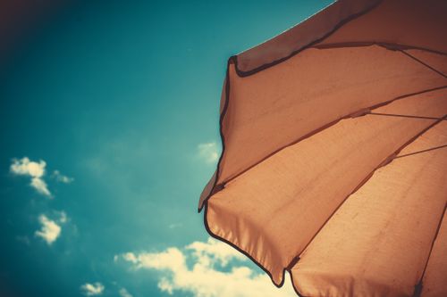 Free Orange parasol against a clear blue sky on a sunny summer day. Stock Photo