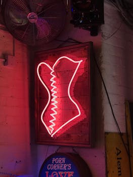 Neon corset sign on a brick wall adds a retro vibe to this dimly lit bar interior.