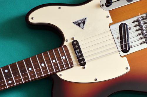 Free Detailed close-up of a classic electric guitar with a sunburst finish on a green backdrop. Stock Photo