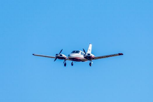 Twin-engine aircraft flying against a bright blue sky.