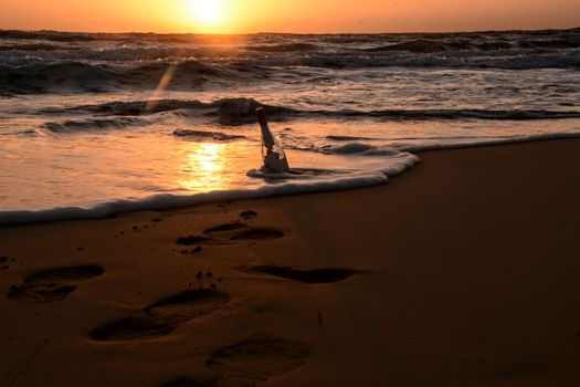 A sunset over Malta's beach with a message bottle in golden surf, evoking mystery and adventure.