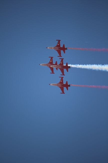Fotomural Cuatro aviones rojos de un equipo acrobático realizando vuelos sincronizados bajo un cielo azul.