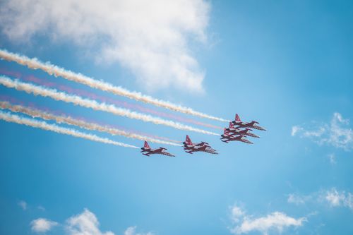 Free A fleet of jet planes performing an aerial display with colorful smoke trails in the bright blue sky. Stock Photo