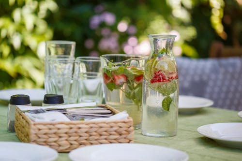 Set of water with lemon and strawberry composing with white plates and tools for eating food