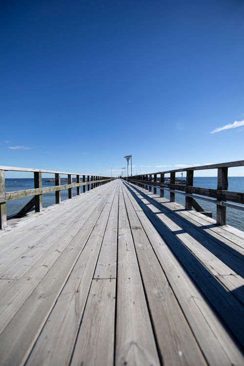 Free Wooden pier in Denmark under a clear blue sky extending over the sea, captured on a sunny day. Stock Photo