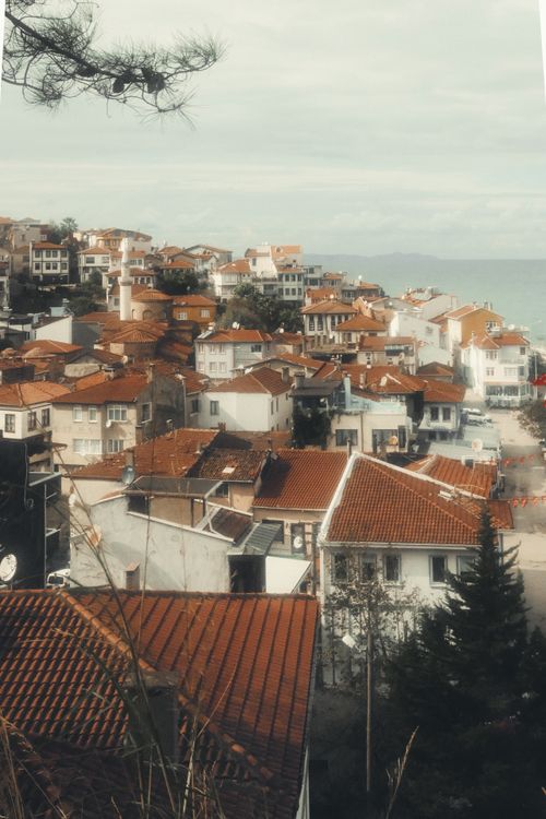 Free Charming coastal view of a Mediterranean town with iconic red rooftops and sea backdrop. Stock Photo