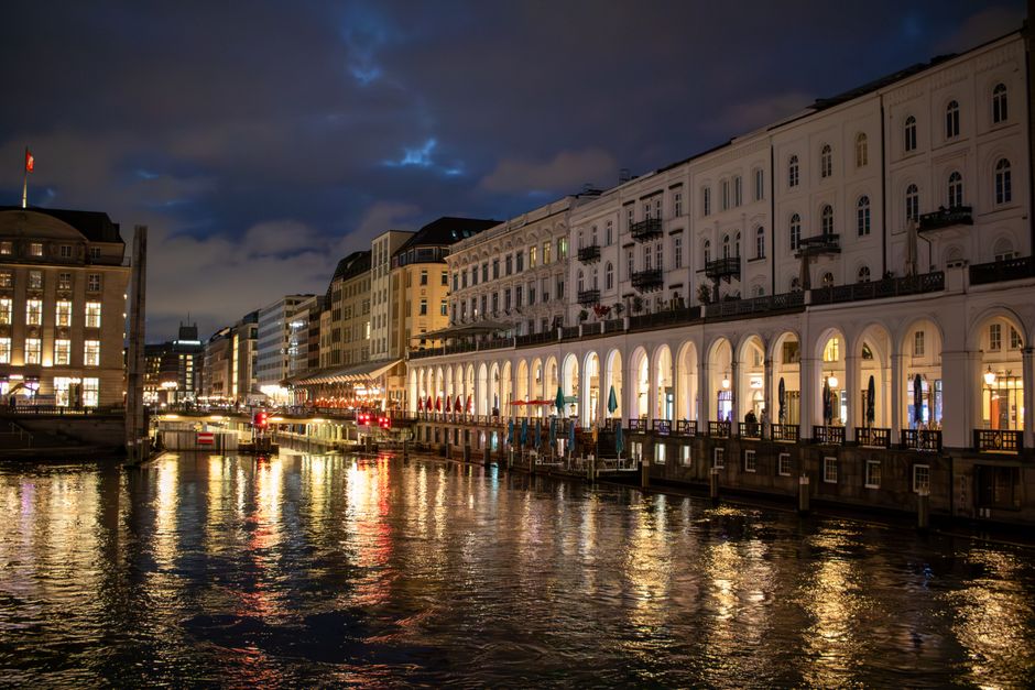 Night view of historic buildings reflecting on Hamburg's canal waters, capturing urban charm and architecture.