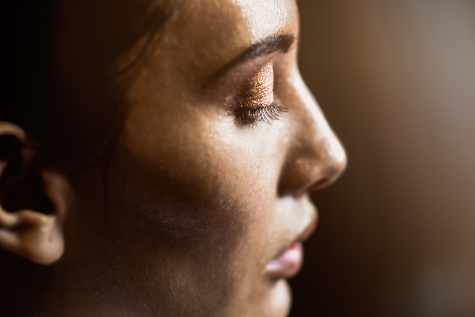 Close-up profile of a woman's face illuminated by warm, directional light highlighting her glowing skin.