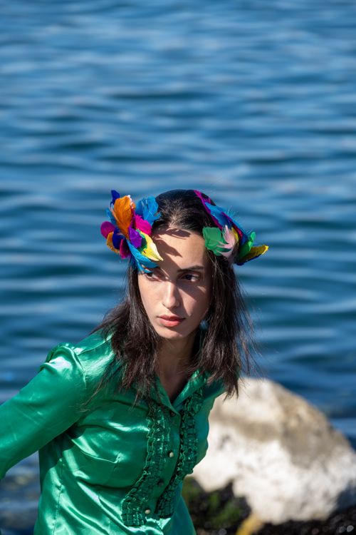 Free Colorful portrait of a woman wearing a feathered headpiece by the waterfront. Stock Photo