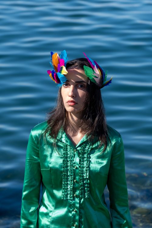 Free Portrait of a woman with colorful feather headpiece by the waterfront. Stock Photo