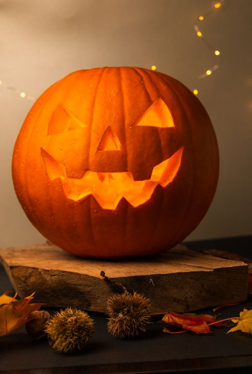 Free A glowing jack-o'-lantern surrounded by autumn leaves, symbolizing Halloween celebration. Stock Photo