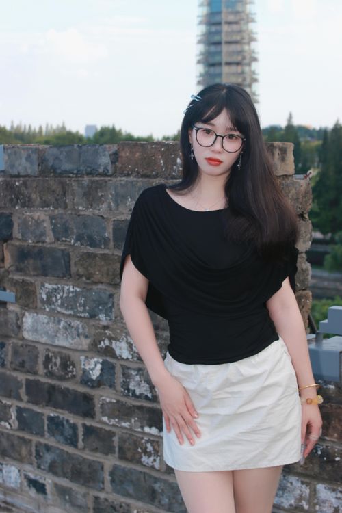 Free Young woman in stylish attire leaning against a brick wall in Nanjing, China. Stock Photo