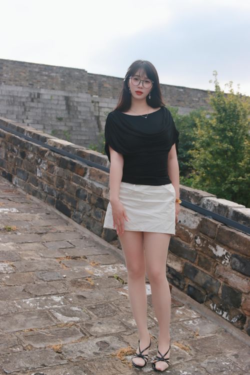 Free Young woman poses stylishly against the backdrop of Nanjing's ancient city wall. Stock Photo