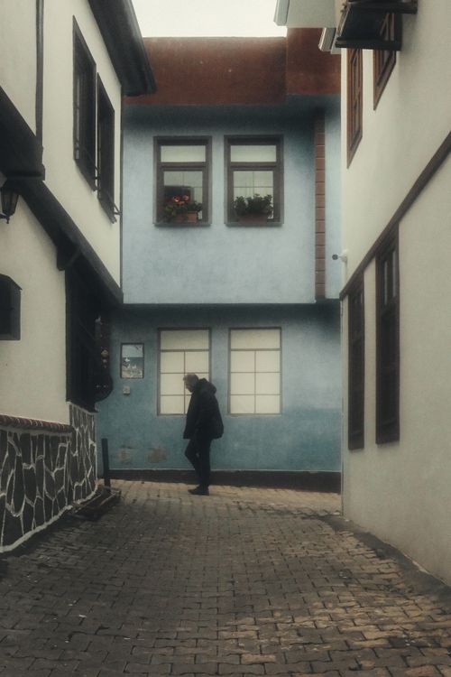 Free A quiet alley with a solitary figure amidst historic architecture. Stock Photo