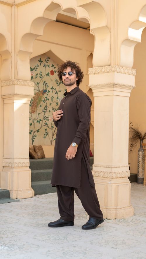 Free Fashionable young man wearing sunglasses and ethnic attire in a traditional courtyard setting. Stock Photo