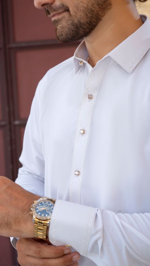 Free Detailed view of a stylish gold watch worn by a man in a formal white shirt. Stock Photo