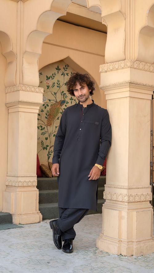 Free Man leaned against pillar in traditional attire, exuding elegance. Stock Photo