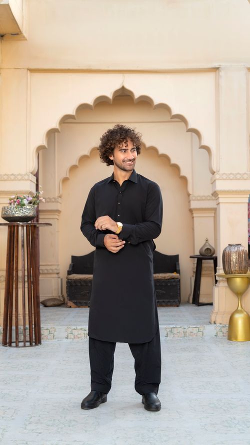 Free Man in a black traditional kurta standing in a classic architectural setting, looking off-camera. Stock Photo