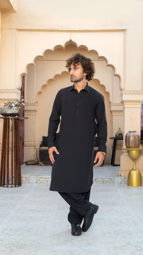 Free A young man in a black kurta poses elegantly in a classical architectural setting. Stock Photo