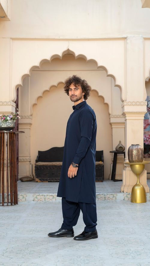 Free Portrait of a man in traditional South Asian attire standing in an ornate indoor setting. Stock Photo