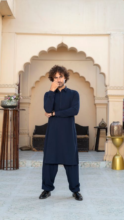 Free A man in traditional attire poses stylishly in a beautifully decorated courtyard with arch details. Stock Photo