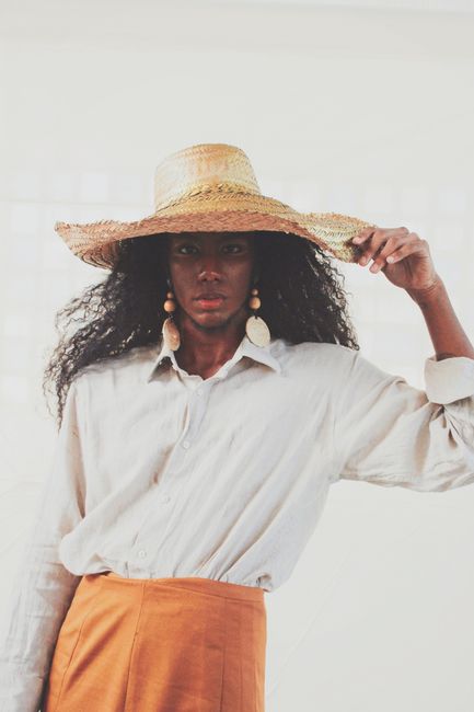 Elegant woman in straw hat with white shirt, showcasing fashion style.