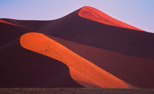 Free Dramatic red and orange dunes in a desert landscape illuminated by sunrise light. Stock Photo