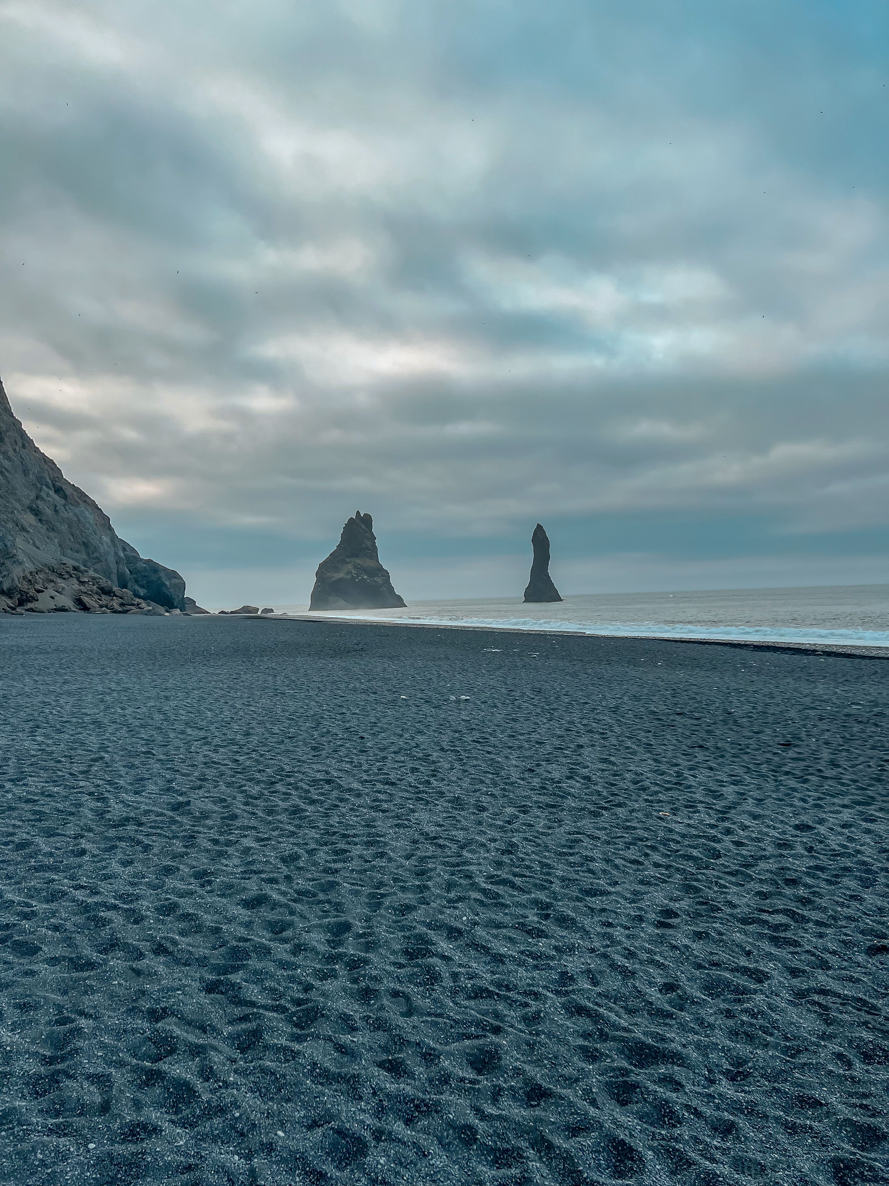Fotomural Vista majestuosa de las pilas de mar de Reynisdrangar en un día nublado en la playa de Vík í Mýrdal, Islandia.