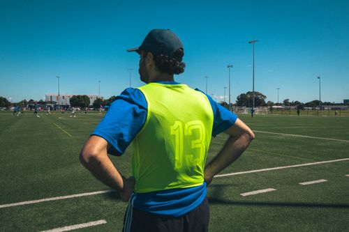 Free An adult male soccer player with number 13 on a bright vest observes a field in Melbourne, Australia. Stock Photo