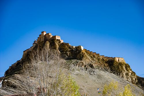 Free A stunning view of a Tibetan fortress atop a rocky hill under a clear blue sky. Perfect for travel enthusiasts. Stock Photo