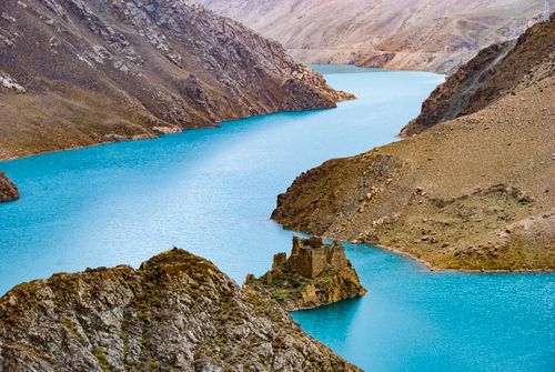 Free A stunning view of a blue mountain lake surrounded by rocky terrain and ancient ruins. Stock Photo