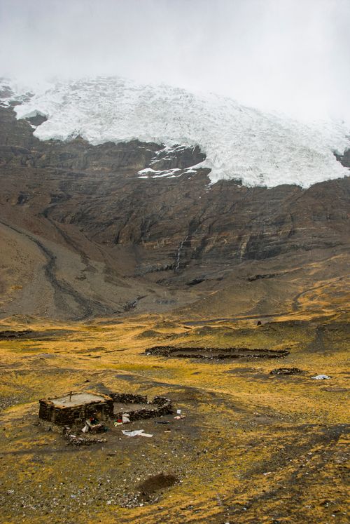 Free A solitary stone hut in a desolate, mountainous region beneath a massive glacier. Stock Photo
