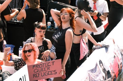 Free A vibrant group celebrating at Amsterdam Pride Parade with a sign for refugee rights advocacy. Stock Photo