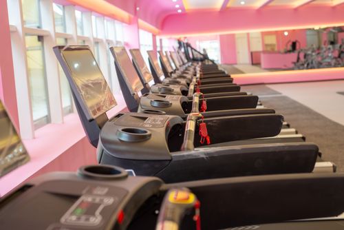 Free A row of modern treadmills in a brightly colored gym interior, perfect for fitness enthusiasts. Stock Photo