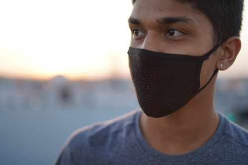 Free Close-up of a young man wearing a black face mask outdoors, at sunset. Stock Photo