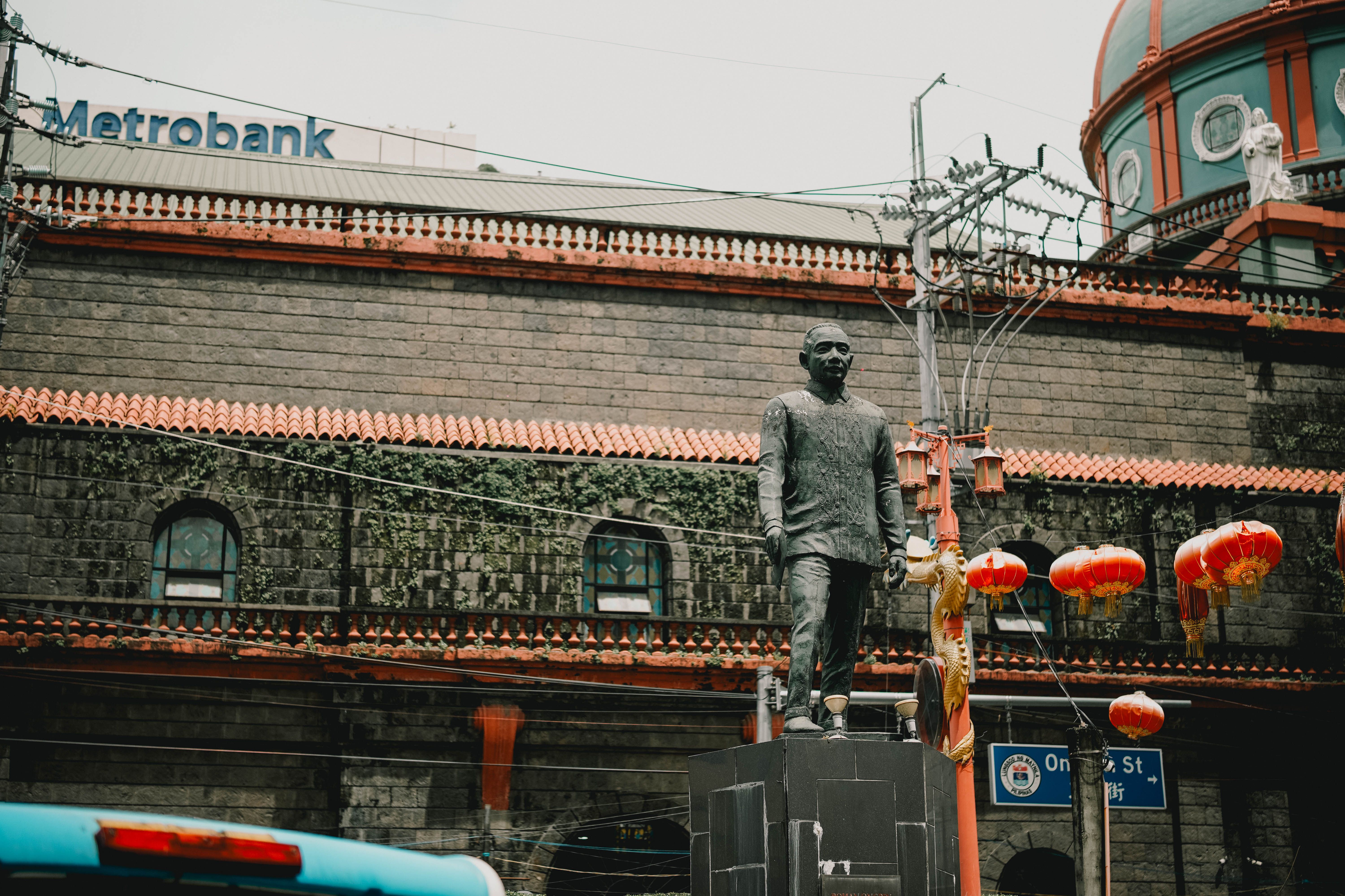 Statue with red lanterns in Manila's Chinatown, vibrant and historic.