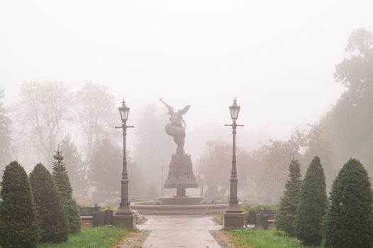 Foggy morning scene of a monument in a Kyiv park, Ukraine.