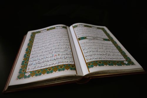 Free The Quran open to a beautifully ornate page with Arabic calligraphy and intricate designs. Stock Photo
